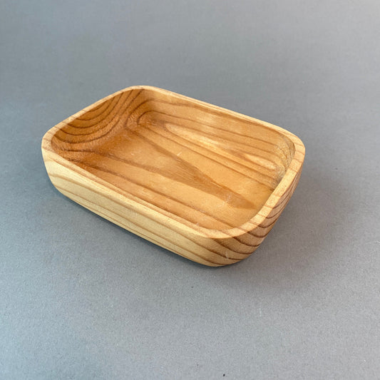 Photo of handmade wooden soap dish on grey background.  Wood has interesting wood grain. 