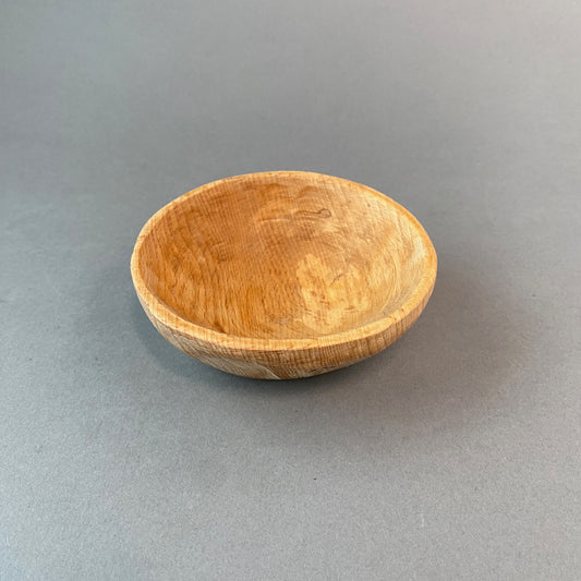 Picture of rustic hand carved wooden bowl on grey background.