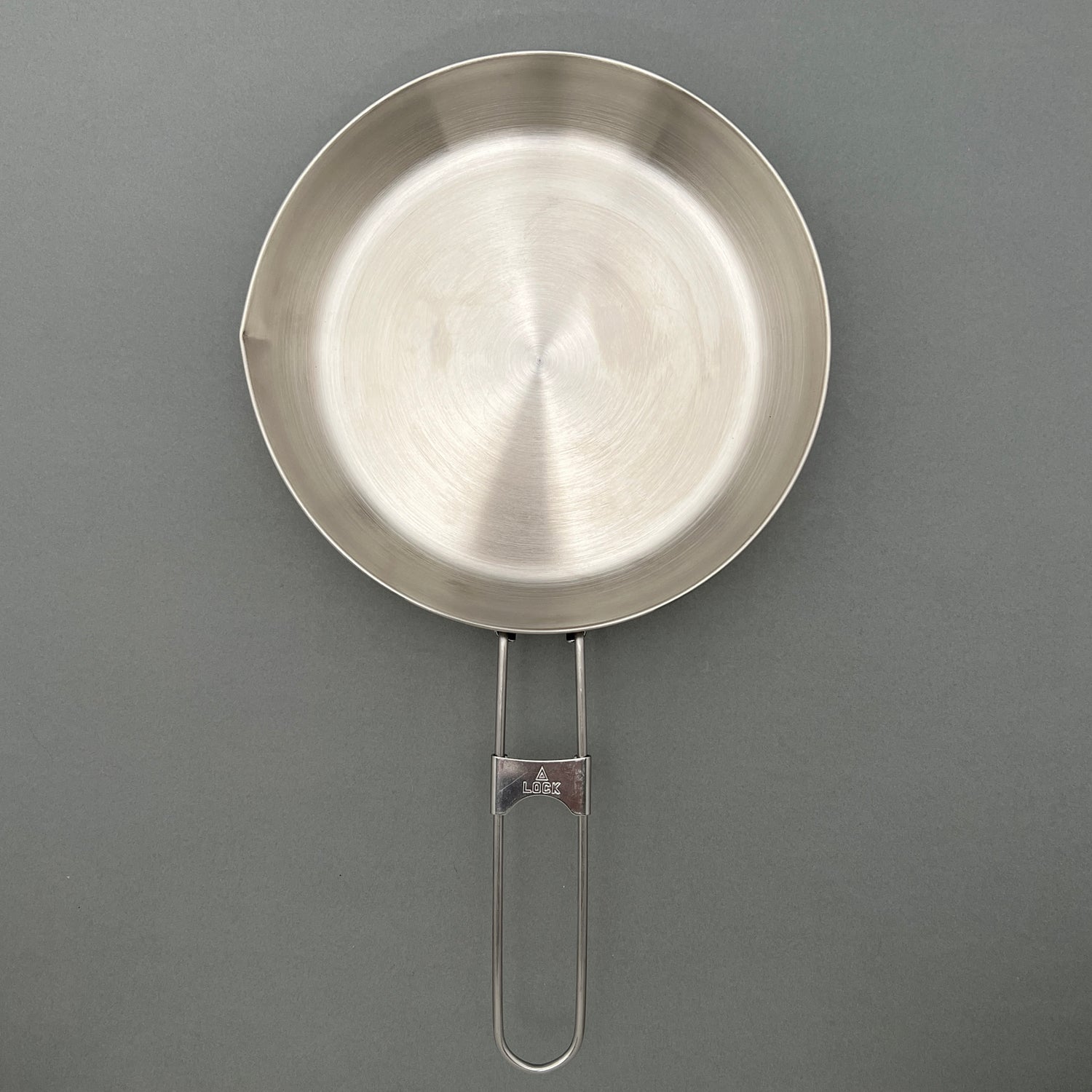 A stainless steel fry pan with a gray background
