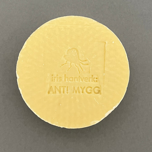 A round yellow handmade anti-mosquito soap from iris hanteverk laying on a gray background