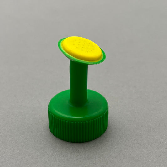 A green plastic bottle cap with a yellow watering nozzle standing on a grey background 