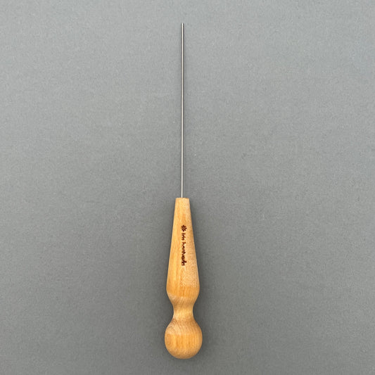A steel cake and potato tester with a wooden handle laying on a gray background