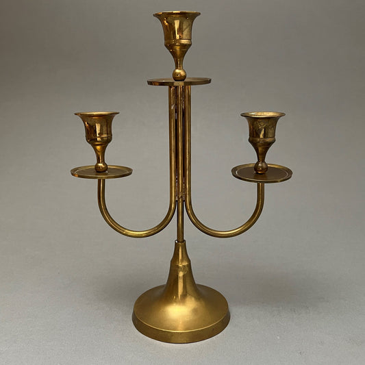 A golden candle holder standing on a gray background