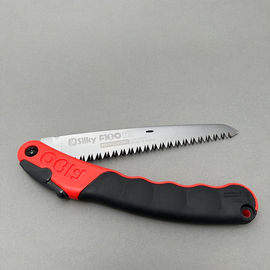 A foldable hand saw laying on a gray background  Edit alt text