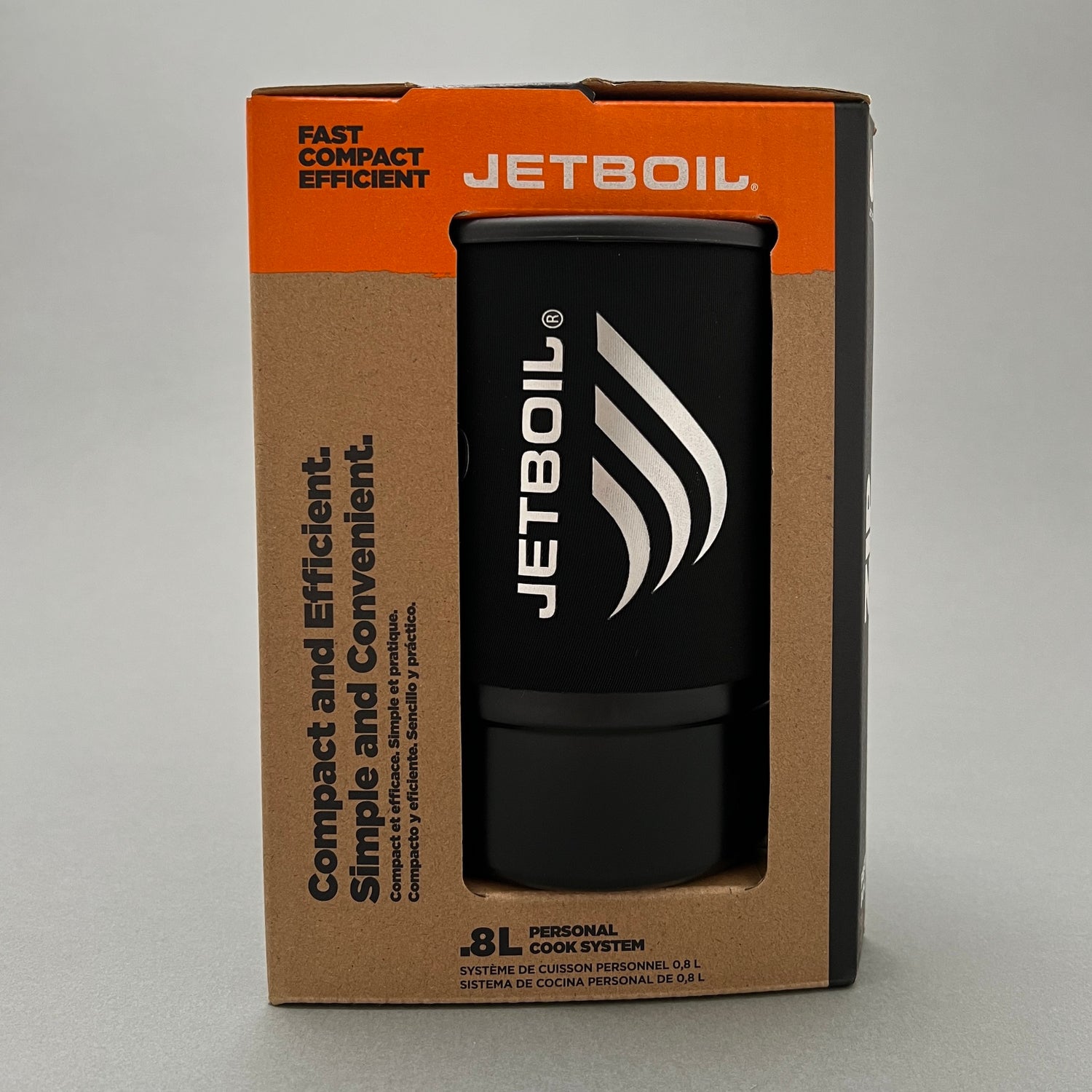 A camping stove from jetboil with a small gas container and a boiling pot inside its package sitting on a gray background