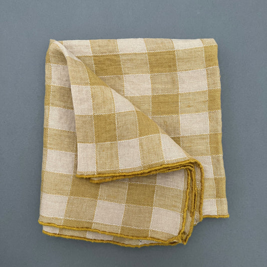 A yellow and white checkered kitchen towel laying on a gray background