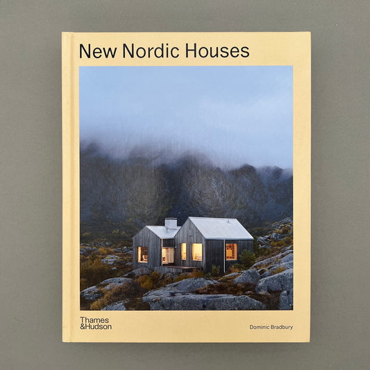 A yellow colored book called "New Nordic Houses" with a picture of a hosue in the mountains on the cover