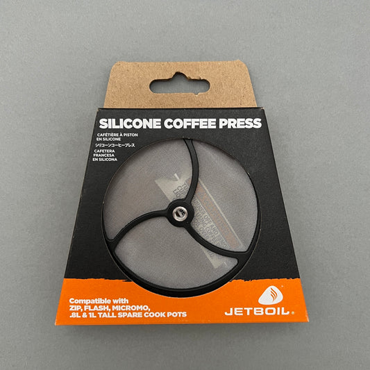 A silicone coffee press inside its package from Jetboil laying on a gray background