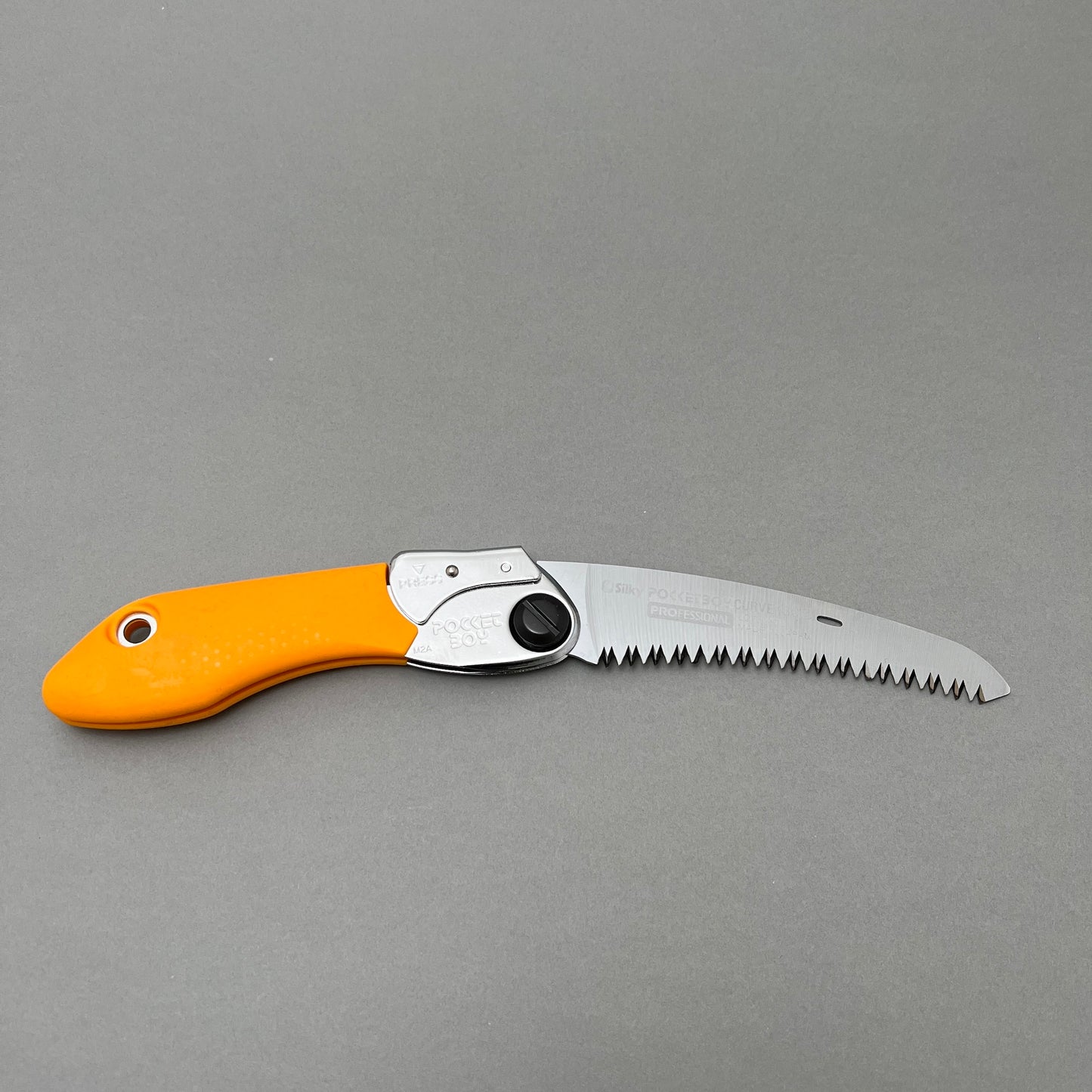 A foldable hand saw laying on a gray background