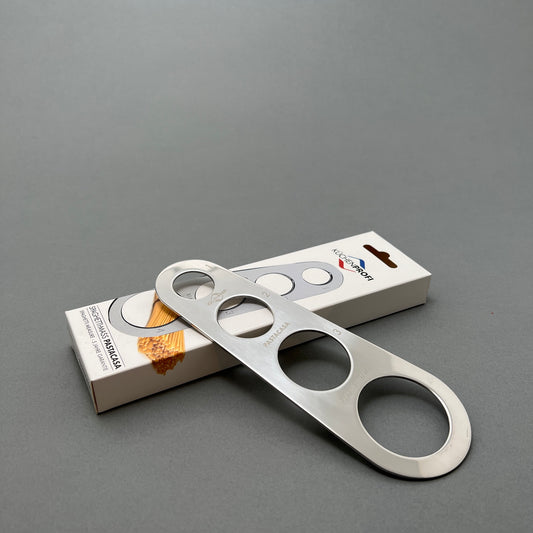 A steel gauge with four different sized holes laying on its cardboard package from kuchenprofi on a gray background