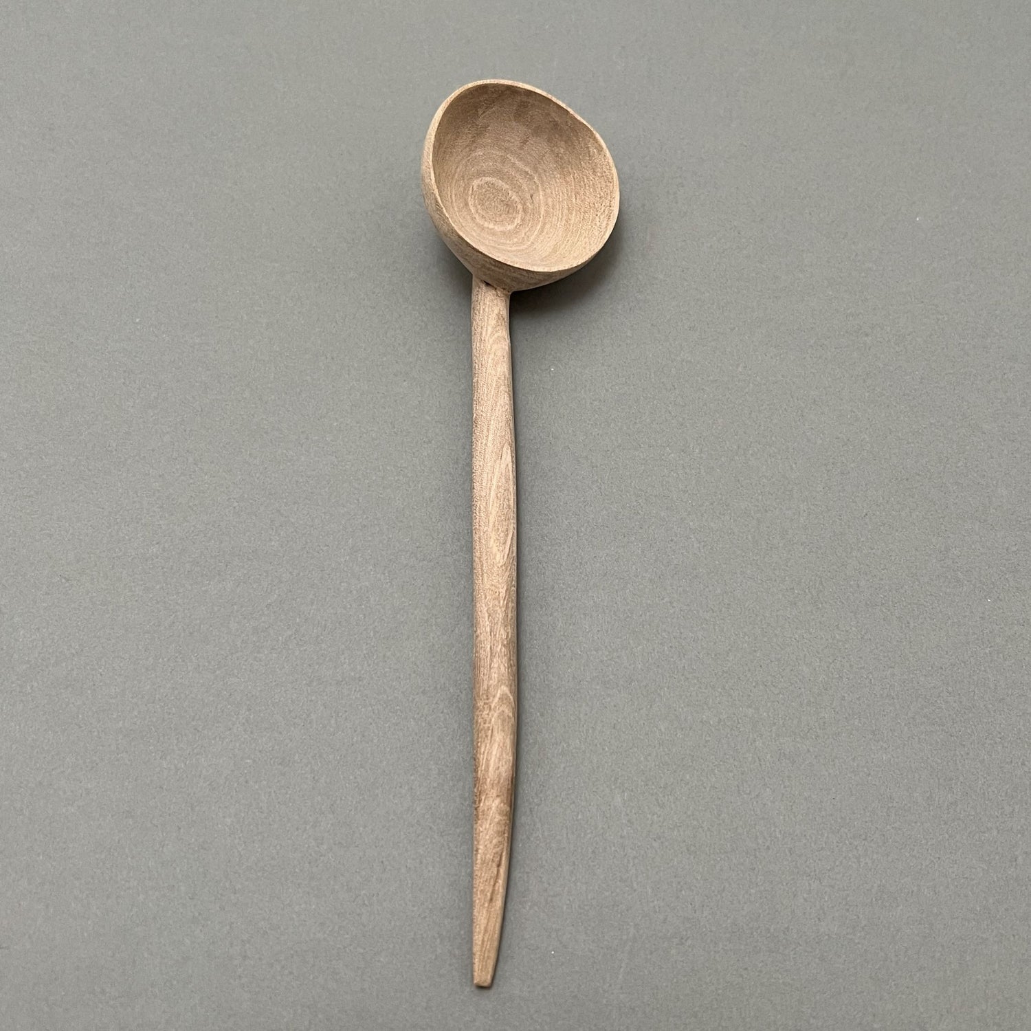 A wooden coffee scoop laying on a gray background