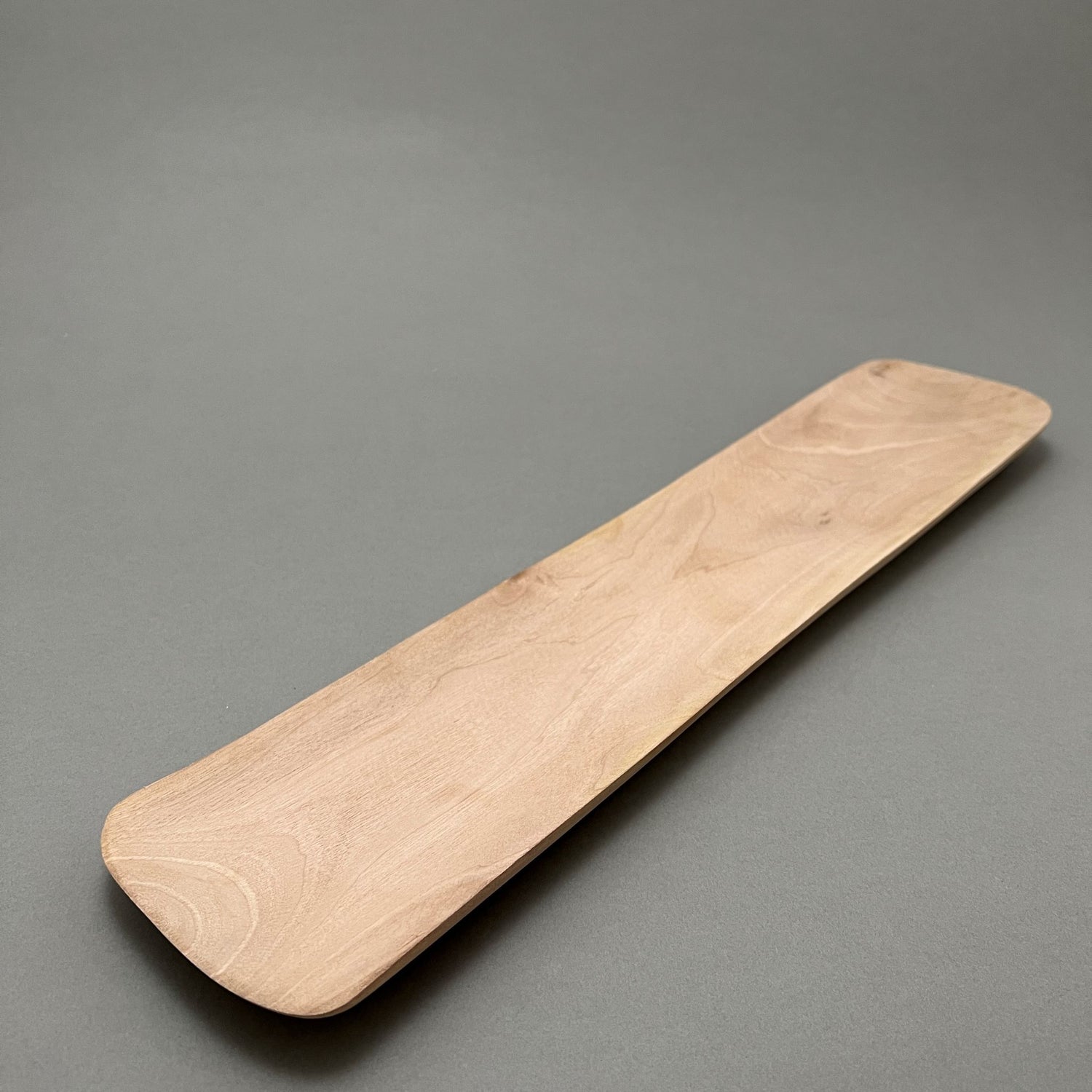 An oblong wooden tray laying on a gray background