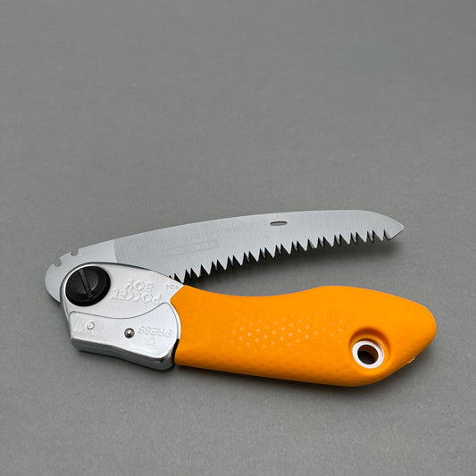 A foldable hand saw laying on a gray background