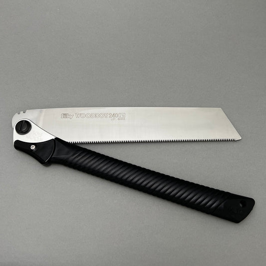 A folded hand saw laying on a gray background