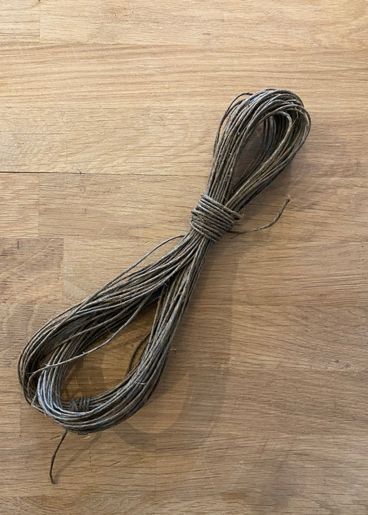 A bundle of brown colored tar twine laying on a wooden bench