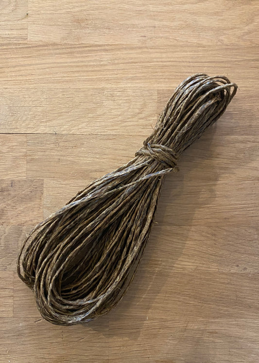 A bundle of brown colored tar twine laying on a wooden bench