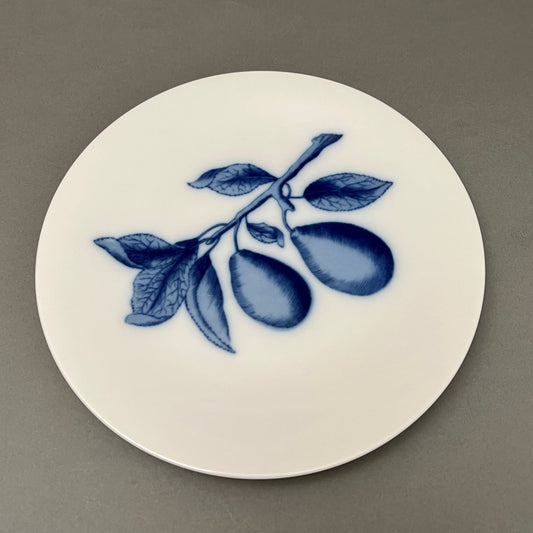 White plate with blue fruit design sitting on gray background