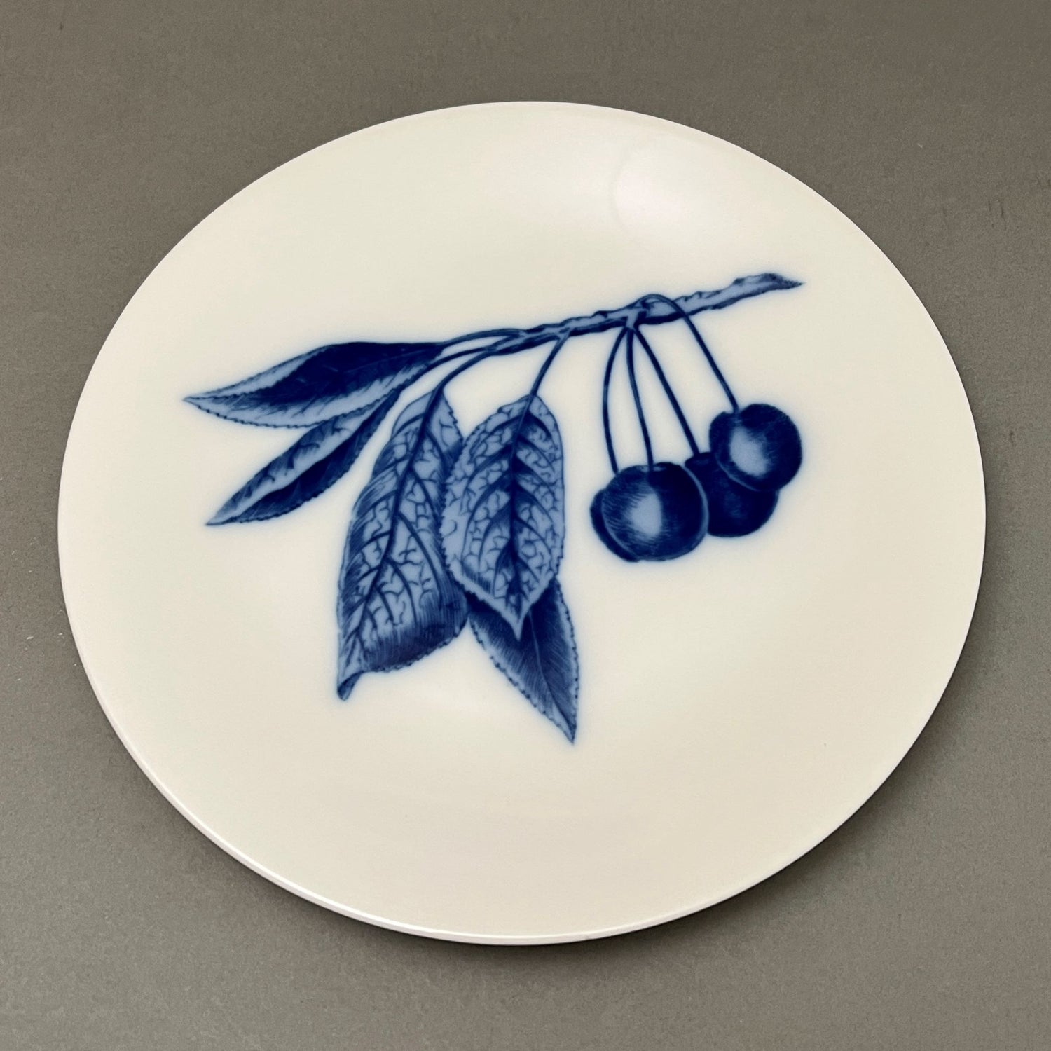 White plate with blue fruit design sitting on gray background