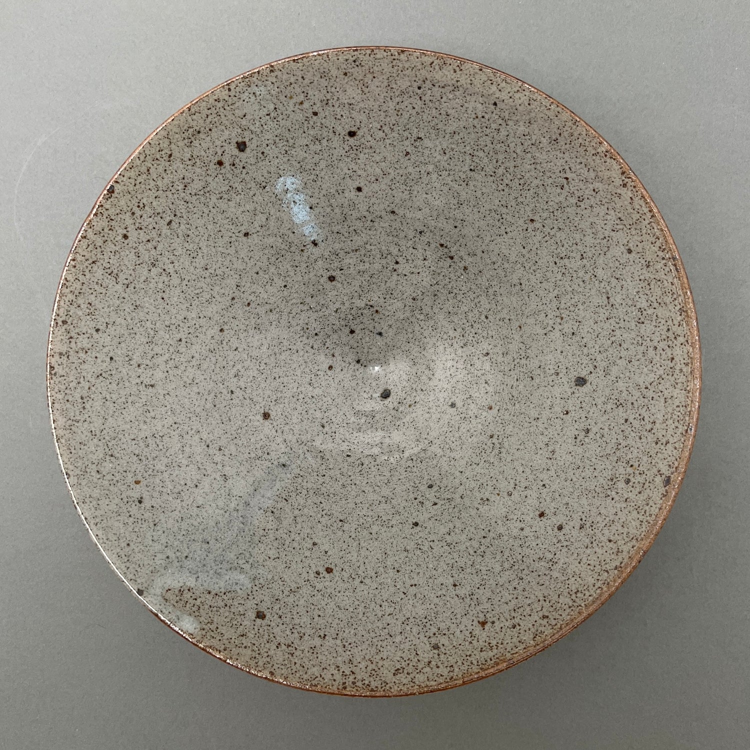 A gray shallow ceramic bowl standing on a gray background