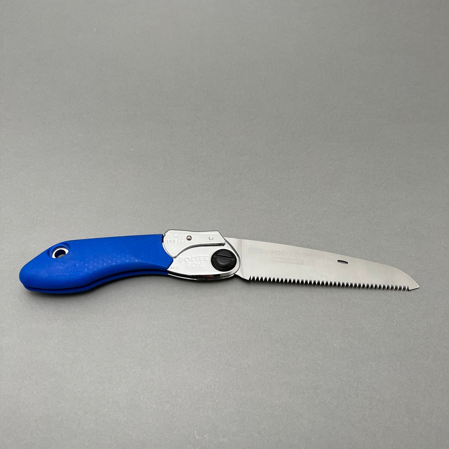 A foldable hand saw laying on a gray background  Edit alt text