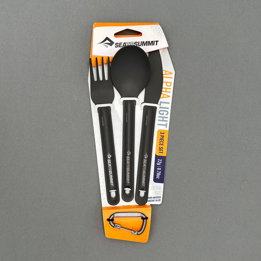 A three piece cutlery set containing a fork, knife and spoon in its package from Sea to Summit laying on a gray background
