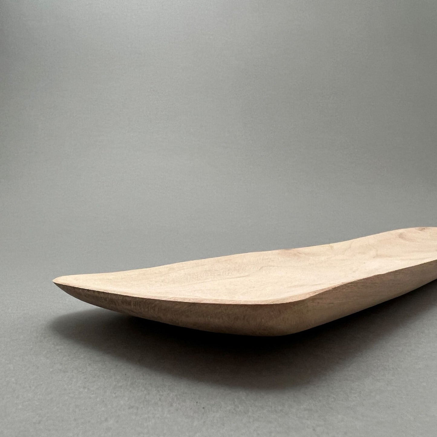 An oblong wooden tray laying on a gray background